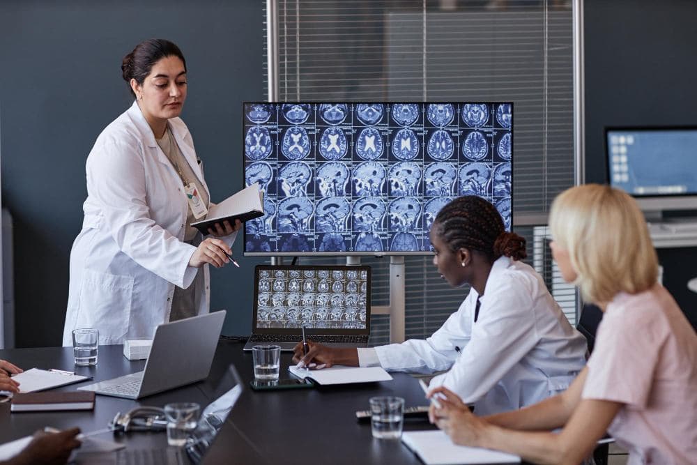 Equipe médica analisando exames de imagem em reunião clínica