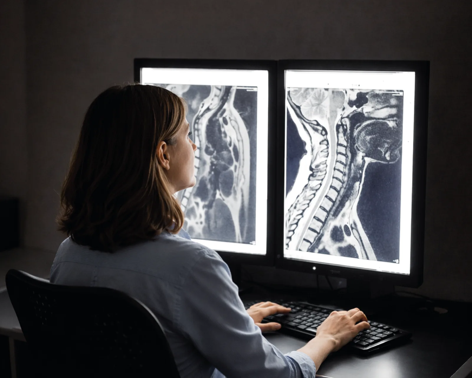 Radiologista analisando exames de ressonância magnética em monitores